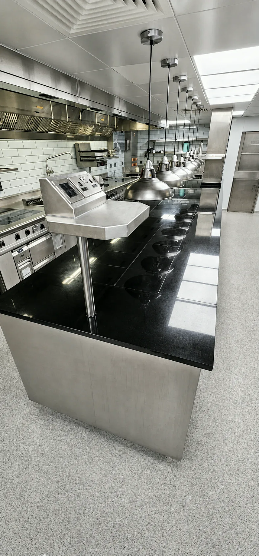 Long black stone commercial kitchen pass with suspended heat lamps